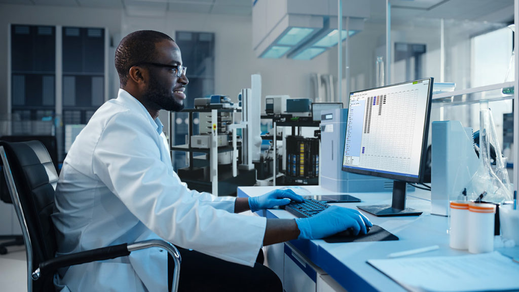 a man in a lab coat looks at a computer