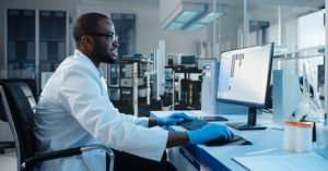 a man in a lab coat looks a computer